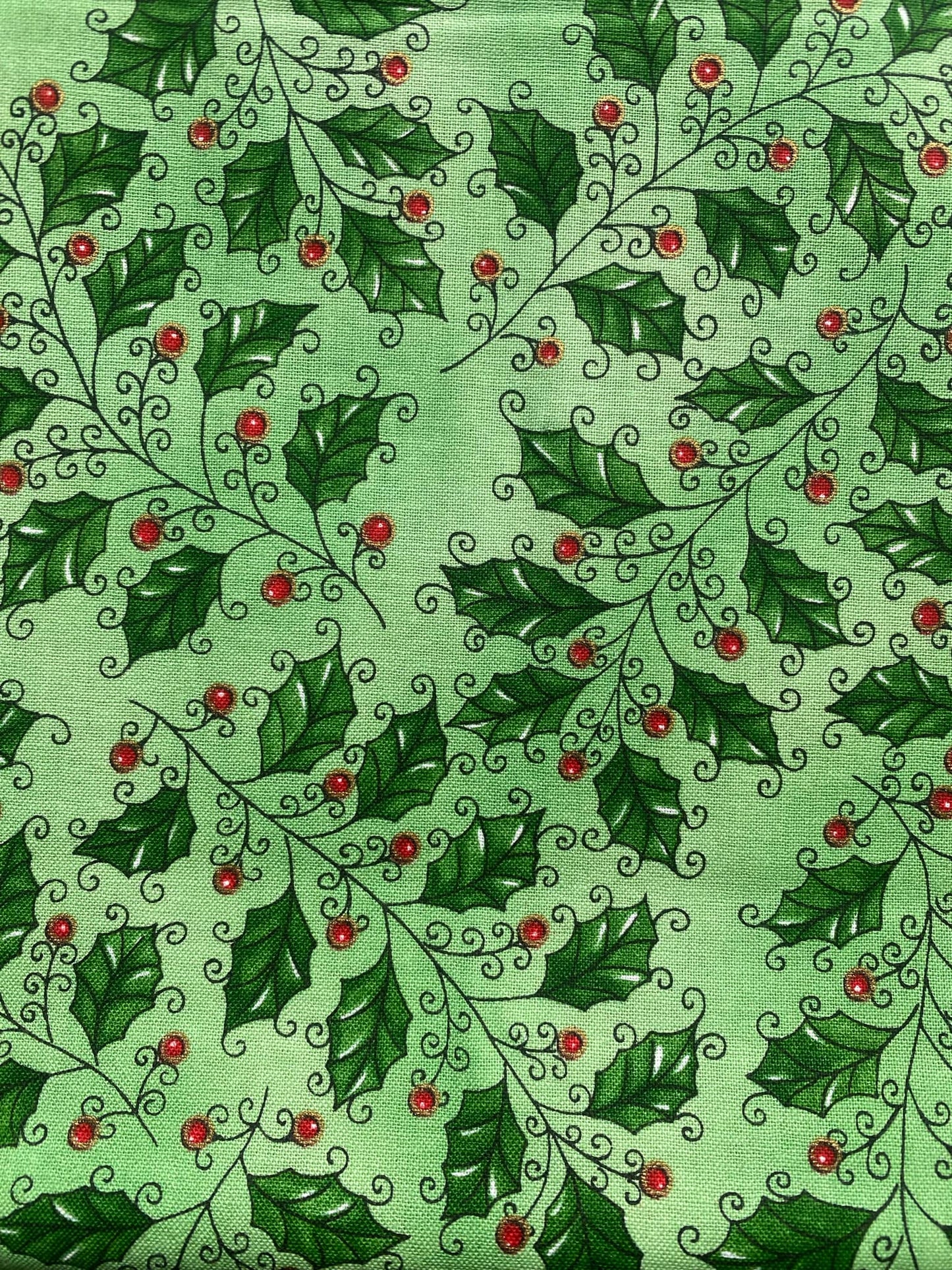 Clothworks Christmas Spirit 100% cotton fabric. Fat Quarter. Green holly leaves with red berries on a green background.